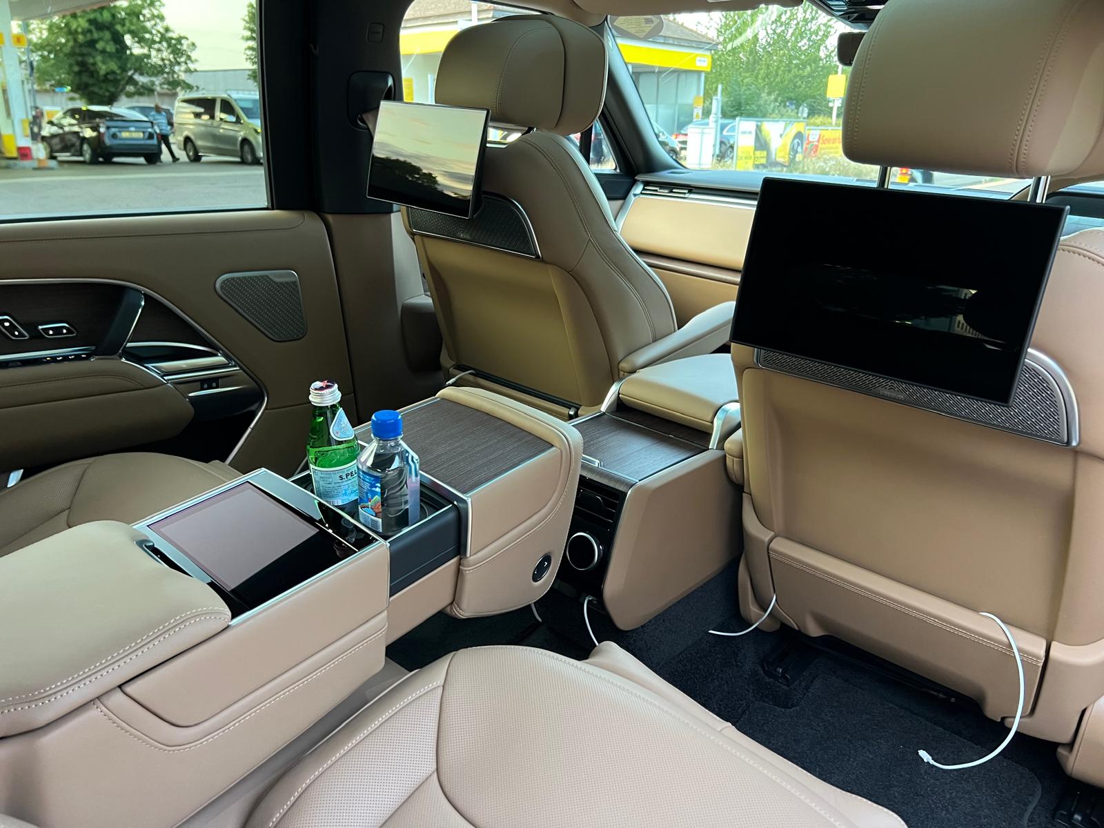 Luxury chauffeur vehicle interior with rear passenger screens and refreshments